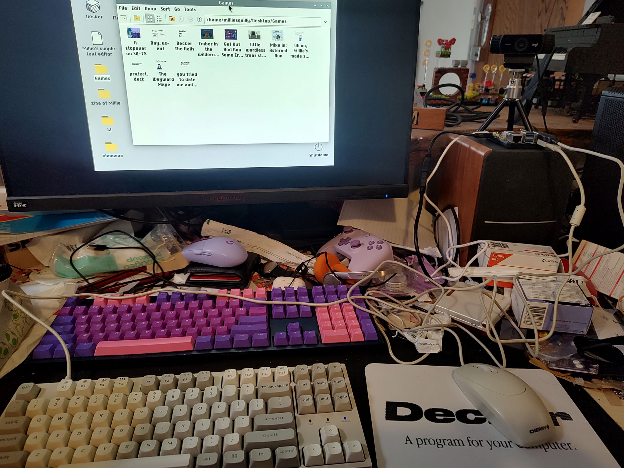 Messy desk with a beige keyboard and mouse hooked up to a raspberry pi displaying a folder of my Decker games on the monitor