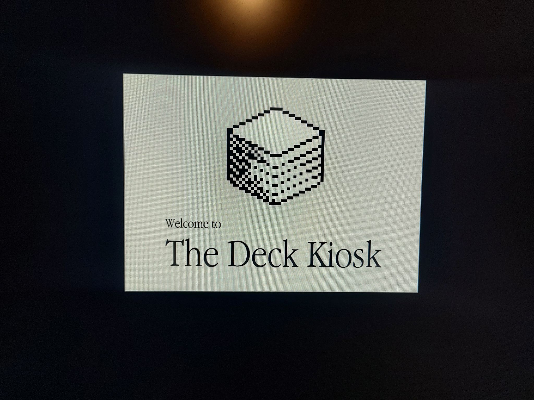 Grey on black screen with Decker logo and the text "Welcome to The Deck Kiosk" in Garamond Narrow